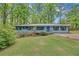 Charming single-story home with blue exterior, manicured lawn, and wooded surroundings at 4856 Rock Haven Dr, Lilburn, GA 30047