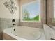 Bright bathroom with a soaking tub and window, decorated with cool, neutral shades at 6915 Rambling Vale, Cumming, GA 30028