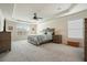 Spacious main bedroom with neutral carpet, a ceiling fan, and tray ceiling, offering a luxurious retreat at 6915 Rambling Vale, Cumming, GA 30028