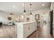 Open-concept kitchen with a large island, modern lighting, and hardwood floors that flow into the living room at 6915 Rambling Vale, Cumming, GA 30028
