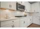 Well-lit kitchen showcasing white cabinets, subway tile backsplash, quartz countertops, and a stainless steel microwave at 6915 Rambling Vale, Cumming, GA 30028