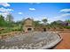 Outdoor patio featuring a stone fireplace, surrounded by a seating area and landscaped gardens at 6915 Rambling Vale, Cumming, GA 30028