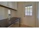 Functional laundry room with tile flooring, a dark wooden table, and exterior access through a white door at 6027 Wintergreen Rd, Norcross, GA 30093