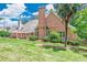This backyard features lush green grass, mature trees, and a stately brick home at 9810 Foxworth Dr, Alpharetta, GA 30022