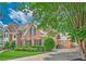 Brick house featuring professionally landscaped front yard and mature trees under a sunny sky at 9810 Foxworth Dr, Alpharetta, GA 30022