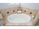 Close-up of corner bathtub with decorative tile, offering a relaxing spa-like experience at 1227 Ashford Creek Ne Park, Atlanta, GA 30319