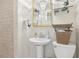Bathroom featuring a pedestal sink, toilet, and decorative mirror and shelves with wicker baskets at 1241 Briarcliff Ne Rd, Atlanta, GA 30306