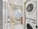 Bright bathroom featuring a glass shower, beige tile, a modern vanity, and washer/dryer at 1241 Briarcliff Ne Rd, Atlanta, GA 30306