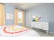 Stylish bedroom with a rainbow blanket, side table, dresser, and ample natural light at 135 Kingsley Way, Acworth, GA 30102