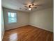 A bright bedroom features hardwood flooring, ceiling fan and a window letting in natural light at 5250 Mountain Village Ct, Stone Mountain, GA 30083
