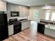Well-lit kitchen features grey cabinetry, black appliances, marble countertops, and stainless farmhouse sink at 212 Lake Forest Dr, Acworth, GA 30102