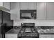 Modern black stainless gas range and microwave with gray cabinets and marble countertops at 212 Lake Forest Dr, Acworth, GA 30102