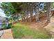 Spacious backyard with a green lawn, trees, and a partial view of a wooden deck and fence at 935 Mill Creek Ave, Canton, GA 30115