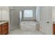 Elegant bathroom with a jetted tub, walk-in shower, and vanity with granite countertops at 4530 Bogan Gates Dr, Buford, GA 30519