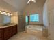 Primary bathroom with soaking tub, shower, tile floors, granite countertops, and lots of natural light at 4530 Bogan Gates Dr, Buford, GA 30519