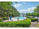 Community pool with chairs, umbrellas, lush landscaping, and a restroom building at 3537 Castle View Ct, Suwanee, GA 30024