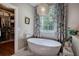 Bright bathroom features a soaking tub under a window with floral curtains and walk-in closet at 3695 Highway 140, Rydal, GA 30171