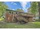 Two story home with a large deck and stairs, set on a well-maintained lawn with lush green trees and foliage at 2648 Woodacres Ne Rd, Atlanta, GA 30345