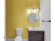 Bathroom with a wood vanity, white toilet, round mirror, and brushed nickel fixtures against a yellow wall at 1043 Lexus Dr, Lawrenceville, GA 30045