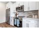 Well-lit kitchen with stainless steel appliances, white cabinetry, and neutral backsplash at 201 Starr Cir, Stockbridge, GA 30281