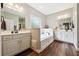 Elegant bathroom featuring double sinks, framed mirrors, stylish lighting, and a garden tub at 825 Kennedy Ct, Loganville, GA 30052