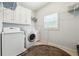 Laundry room featuring a front-load washing machine, dryer, and white cabinets at 825 Kennedy Ct, Loganville, GA 30052