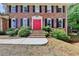 Close-up of brick home's front entrance with vibrant red double doors and classic black shutters at 1450 Holly Bank Cir, Atlanta, GA 30338