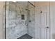 Shower with glass door, marble tile surround, shower niche, and black and white mosaic floor at 1450 Holly Bank Cir, Atlanta, GA 30338