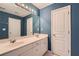 Bathroom featuring a double sink vanity, large mirror, and blue walls at 3733 Sidney Lanier Blvd, Duluth, GA 30096