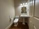 Elegant half bathroom featuring a pedestal sink, decorative mirror, and stylish fixtures at 608 Tabbystone Nw St, Marietta, GA 30064