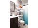 This bathroom includes a toilet with rack, blue shower curtain, sink, mirror, and decorative accents at 1452 Mercer Ave, Atlanta, GA 30337