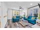 Bright living room featuring hardwood floors, blue couches, large windows, and a ceiling fan at 1452 Mercer Ave, Atlanta, GA 30337