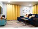 Inviting living room with a comfortable blue sofa, wood floors, and bright yellow curtains at 1452 Mercer Ave, Atlanta, GA 30337