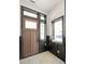 Modern entryway with a wood door, black trim, light tile flooring, and natural light from surrounding windows at 11530 Serenbe Ln, Chattahoochee Hills, GA 30268
