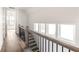 Bright upstairs hallway with hardwood floors, a dark metal railing, and natural light from the windows at 11530 Serenbe Ln, Chattahoochee Hills, GA 30268