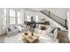 Bright living room featuring a modern sofa, stylish decor, staircase, and an open floor plan at 11530 Serenbe Ln, Chattahoochee Hills, GA 30268