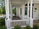 A charming front porch with white columns, brick flooring, and manicured landscaping at 11530 Serenbe Ln, Chattahoochee Hills, GA 30268