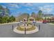 Community entrance with circular fountain, manicured landscaping, and visitor parking at 116 Via Roma, Woodstock, GA 30188