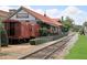 Exterior view of restaurant with a train car on display, railroad track, and greenery at 116 Via Roma, Woodstock, GA 30188