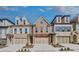 Charming townhome showcasing stone and brick facade, multiple windows, and covered garages at 116 Via Roma, Woodstock, GA 30188