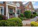 Charming brick home featuring a welcoming front porch with decorative details and manicured landscaping at 227 Cedarhurst Dr, Canton, GA 30115