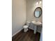 Half bathroom featuring hardwood floors, pedestal sink, toilet, and round mirror at 2285 Crossrail Dr, Atlanta, GA 30349