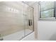 A bathroom featuring a glass-enclosed bathtub/shower, white tile walls, and a window with natural light at 4514 Creekwood Nw Cir, Kennesaw, GA 30152
