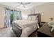 A cozy bedroom featuring a queen-sized bed, ceiling fan, and natural light from the sliding glass door to a balcony at 4514 Creekwood Nw Cir, Kennesaw, GA 30152