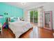 Cheerful bedroom with hardwood floors, a queen-sized bed, a glass sliding door to a balcony, and aqua accent wall at 4514 Creekwood Nw Cir, Kennesaw, GA 30152