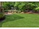 Spacious backyard with a large lawn, mature trees, and a partial view of the home at 2437 Camden Lake Nw Vw, Acworth, GA 30101