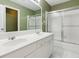 This is a bathroom with double sinks, white cabinetry, a large mirror, and a glass-enclosed shower and tub at 2437 Camden Lake Nw Vw, Acworth, GA 30101