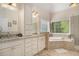 Bright bathroom features dual sink vanity, tub and large window with blinds at 2628 Hollow Pne, Conyers, GA 30094