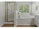 Bright bathroom featuring a tub, shower, and a large window with wooded views at 1575 Wynridge Pointe, Alpharetta, GA 30005