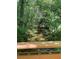 Scenic view of a creek with clear water flowing between lush greenery, framed by a wooden railing at 4774 Olde Village Ln, Atlanta, GA 30338